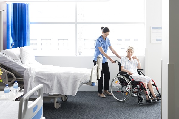 Mature woman in wheelchair with nurse in hospital room